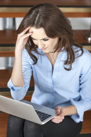 Young woman using a laptop computer looking concerned and worried